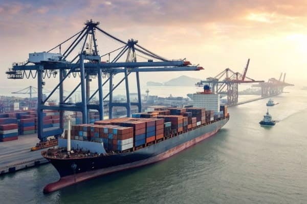 A large container ship at a port being loaded with shipping containers