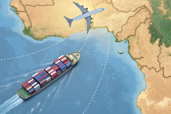 Cargo ship with colorful containers sailing near Africa with airplane flying overhead, illustrating global shipping routes.