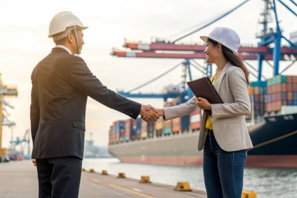 A person shaking hands with a freight forwarder in front of a port