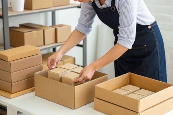 A person consolidating several small boxes into one larger shipping box