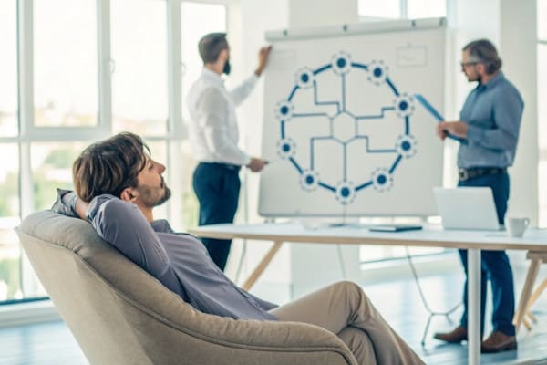 A person relaxing while a team of experts handles a complex supply chain diagram