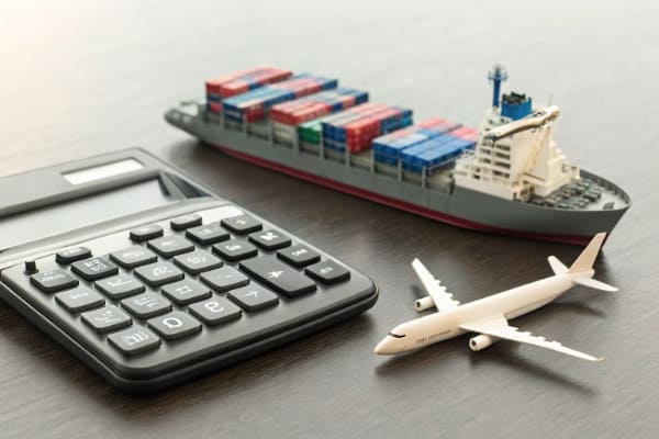A calculator next to a miniature container ship and airplane