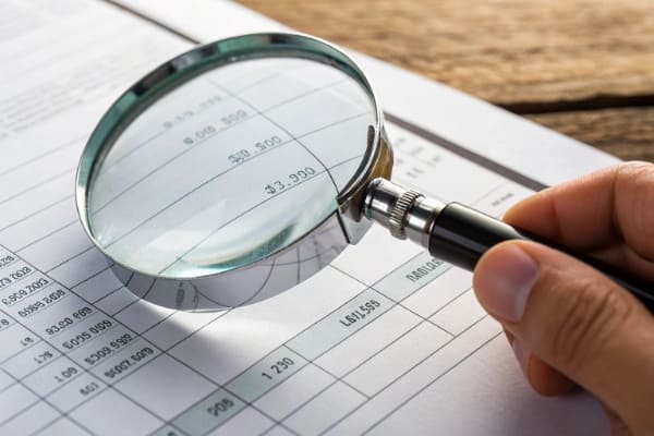 A magnifying glass over a shipping invoice showing hidden fees
